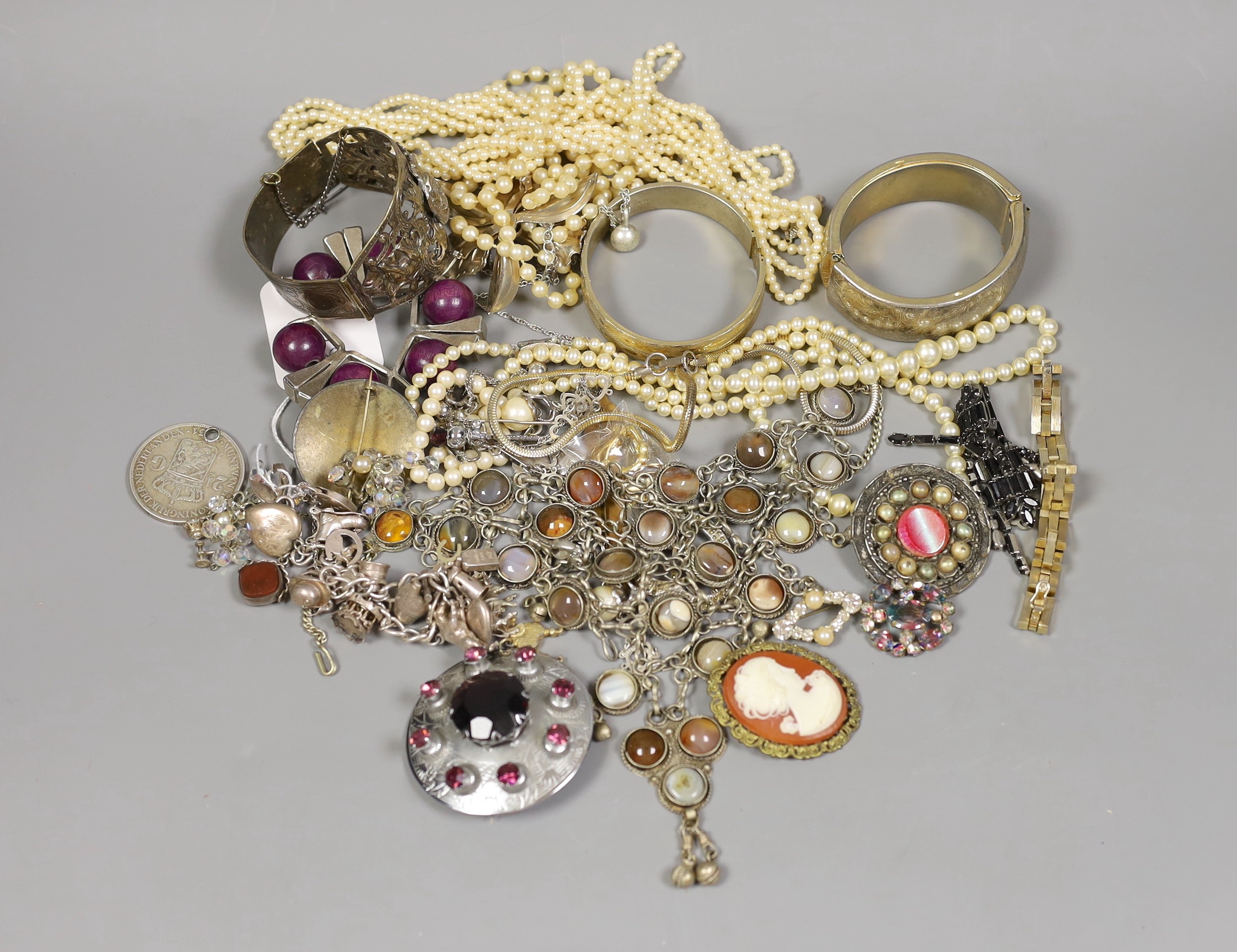 Assorted costume jewellery including a silver charm bracelet, hung with various charms including merry-go-round and bull.